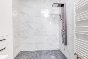 y baño con ducha y paredes de mármol blanco. en Modern House 7min to Paris Professionals and Family, en Alfortville