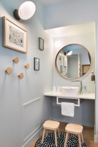 La salle de bains est pourvue d'un lavabo, de deux tabourets et d'un miroir. dans l'établissement Hôtel Diana Restaurant & Spa by HappyCulture, à Molsheim