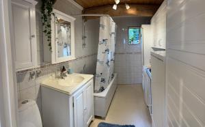 a white bathroom with a sink and a shower at Timber house with private beach and boat including. in Njurundabommen