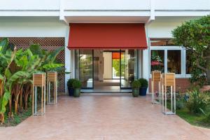 een ingang naar een gebouw met stoelen en een rode luifel bij La Serena Hotel FDM in Forte dei Marmi