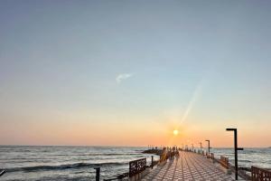 een pier strekt zich uit in de oceaan bij zonsondergang bij H&E Sea view 2-Bedroom Apt Qerret in Golem