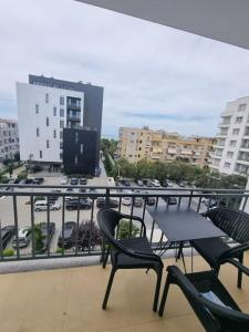 een balkon met stoelen, een tafel en een televisie bij H&E Sea view 2-Bedroom Apt Qerret in Golem