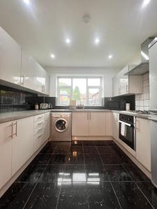 eine Küche mit weißen Schränken, einer Waschmaschine und einem Trockner in der Unterkunft House in the Heart of Manchester in Manchester