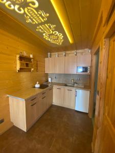 a kitchen with wooden walls and a ceiling with a yellow light at Domek w górach in Nowy Targ