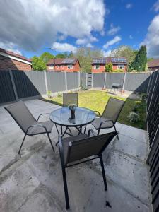 a patio with two chairs and a glass table at House in the Heart of Manchester in Manchester