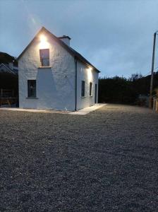 a white building with a window on the side of it at Fox's Cottage in Millstreet