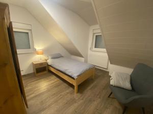 a small bedroom with a bed and a chair at Colmdorf Ferienhaus in Bayreuth