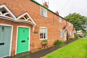 a brick house with green doors and a yard at Finest Retreats - Marmaduke Cottage in Sancton