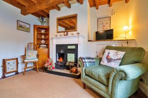 a living room with a green chair and a fireplace at Finest Retreats - Marmaduke Cottage in Sancton