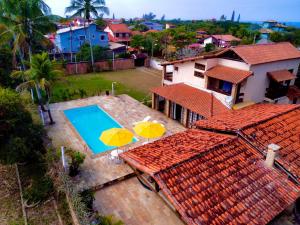 - une vue aérienne sur une maison avec une piscine et deux parasols dans l'établissement CasaGrandeItaúna - Casa na praia de Itaúna, Saquarema, ideal para famílias e você amante do surf - petfriendy, à Saquarema
