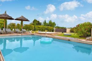 - une piscine d'eau bleue avec des parasols dans l'établissement La Villa aux Parasols, à Saint-Laurent-des-Arbres