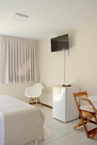 a bedroom with a bed and a tv and a chair at Pousada Estrela Mares in Guarda do Embaú