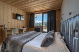 a bedroom with a bed and a desk and a window at Chalet-Hôtel Les Rhodos in Cordon +48 photos