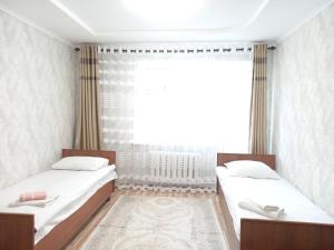 two beds in a room with a window at Dasha Guest House 2 in Naryn