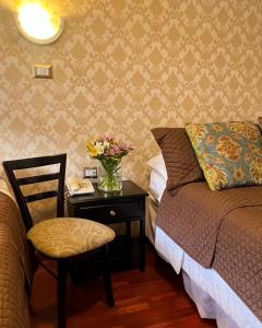 Un dormitorio con una cama y una mesa con un jarrón de flores en HOSTAL EL CAJAS, en Cuenca