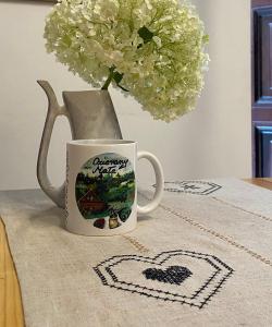 eine Kaffeetasse und eine Vase mit Blumen auf dem Tisch in der Unterkunft Ozierański Eden "Pod rzeźbami" 
