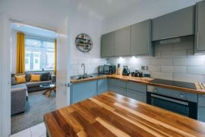 une cuisine avec des placards bleus et une table en bois dans l'établissement Hanson House, à Redcar