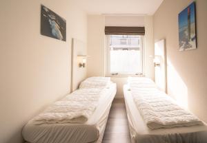 eine Reihe von Betten in einem Zimmer mit Fenster in der Unterkunft Appartementencomplex Juliana 80 in De Koog