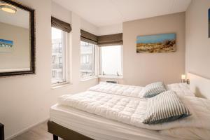 ein Schlafzimmer mit einem großen Bett und zwei Fenstern in der Unterkunft Appartementencomplex Juliana 80 in De Koog