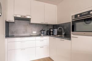 eine weiße Küche mit weißen Schränken und einer Mikrowelle in der Unterkunft Appartementencomplex Juliana 80 in De Koog