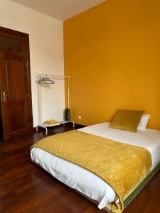 a bedroom with a bed with a yellow wall at Casa Beija-Flor in Mogofores
