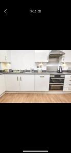 cocina con armarios blancos y fogones en Immaculate 2-Bed Apartment in Romford, en Romford