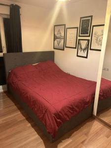 a bedroom with a bed with a red comforter at Immaculate 2-Bed Apartment in Romford in Romford