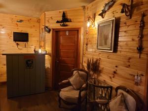 Zimmer mit Holzwänden, Stühlen und einem TV in der Unterkunft Balim Sultany in Cesme