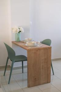 drewniany stół z 2 krzesłami i stół z kwiatami w obiekcie Orfhl Studio w mieście Missolungi