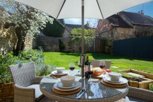 a table with glasses of wine and an umbrella at Bank House in Chipping Campden
