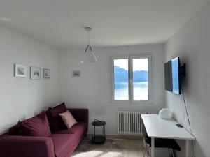 a living room with a purple couch and a window at Room with 360° view overlooking Lake Geneva and Alps in Puidoux
