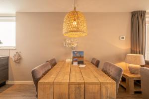 une salle à manger avec une table en bois et un lustre dans l'établissement Appartementencomplex Juliana 34, à De Koog