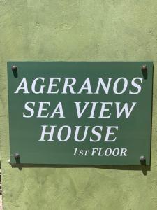 una señal para una casa con vistas al mar en una pared verde en Ageranos seaview house, en Kamáres
