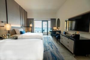 a hotel room with two beds and a flat screen tv at Amwaj Rotana, Jumeirah Beach - Dubai in Dubai