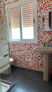 a bathroom with a toilet and a sink and two windows at Appartements Armonía Sea View in Briech