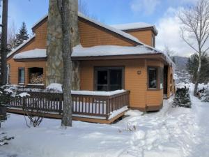 a house with a porch in the snow at FC54 large mountain cottage with views in Bretton Woods