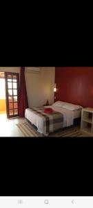 - une chambre avec 2 lits et un mur rouge dans l'établissement Casa do Jardim, à Canoa Quebrada