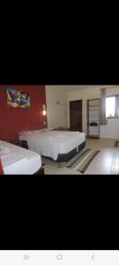 a large room with two beds and a window at Casa do Jardim in Canoa Quebrada