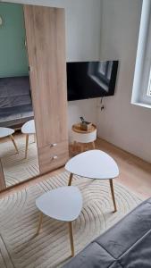 uma sala de estar com duas mesas brancas e uma televisão em Superbe T2 proche gare & centre em Amiens