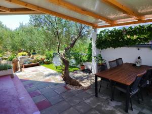 a patio with a wooden table and a tree at Mobile house Green garden in Murter