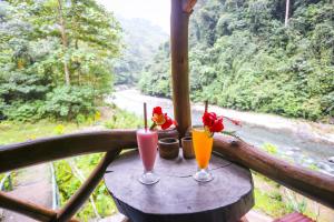 two drinks on a table with a view of a river at back to nature ecotourism in Bukit Lawang