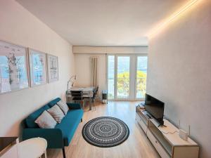 a living room with a blue couch and a television at Brissaghino al Lago 5* in Brissago