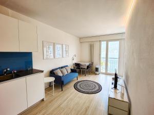 sala de estar con sofá azul y cocina en Brissaghino al Lago 5*, en Brissago