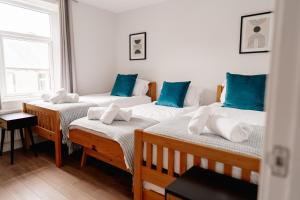 a group of three beds in a room with blue pillows at Sawley Cottage in Skipton