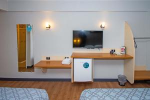 Habitación hospitalaria con escritorio y TV en la pared en H+ Hotel, en Dourados