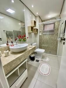 um banheiro com pia, vaso sanitário e chuveiro em APTO 14 - ENSEADA, PRÓXIMO REGIÃO DO PÃO DE AÇUCAR no Guarujá