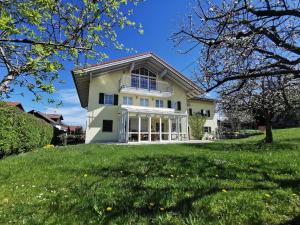 a house on a green lawn with trees at Ferienwohnung Sonnenschein in Rieden am Forggensee