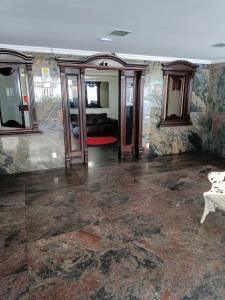 an empty living room with a couch and mirrors at Pe na Areia Ótimo Apto Vista Mar in Praia Grande