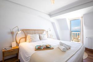 a white bedroom with a bed with a tray of food on it at Far Out Inn - Yoga guesthouse in San Sebastián