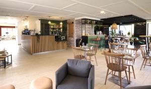 a restaurant with tables and chairs and a bar at Campanile Nature - Taverny in Taverny
